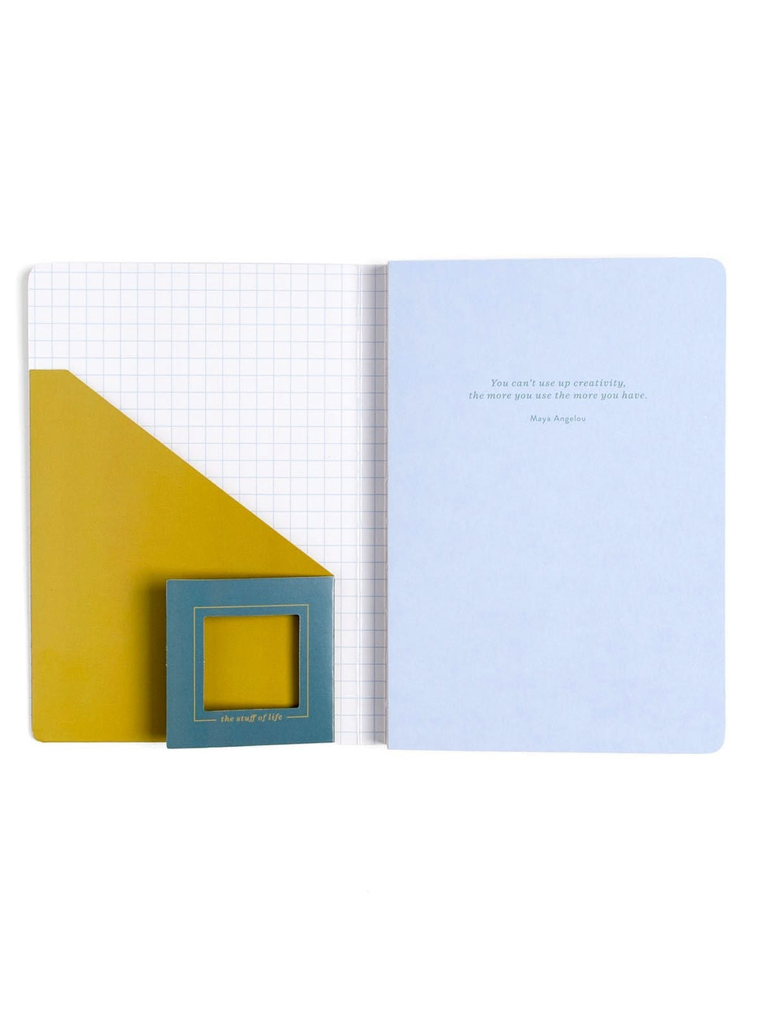 An open notebook or journal with a pale blue right page containing a small quote, a white left page with a grid pattern, and a large mustard yellow geometric accent on the left. A small teal square card with a yellow center is tucked into the lower left corner.