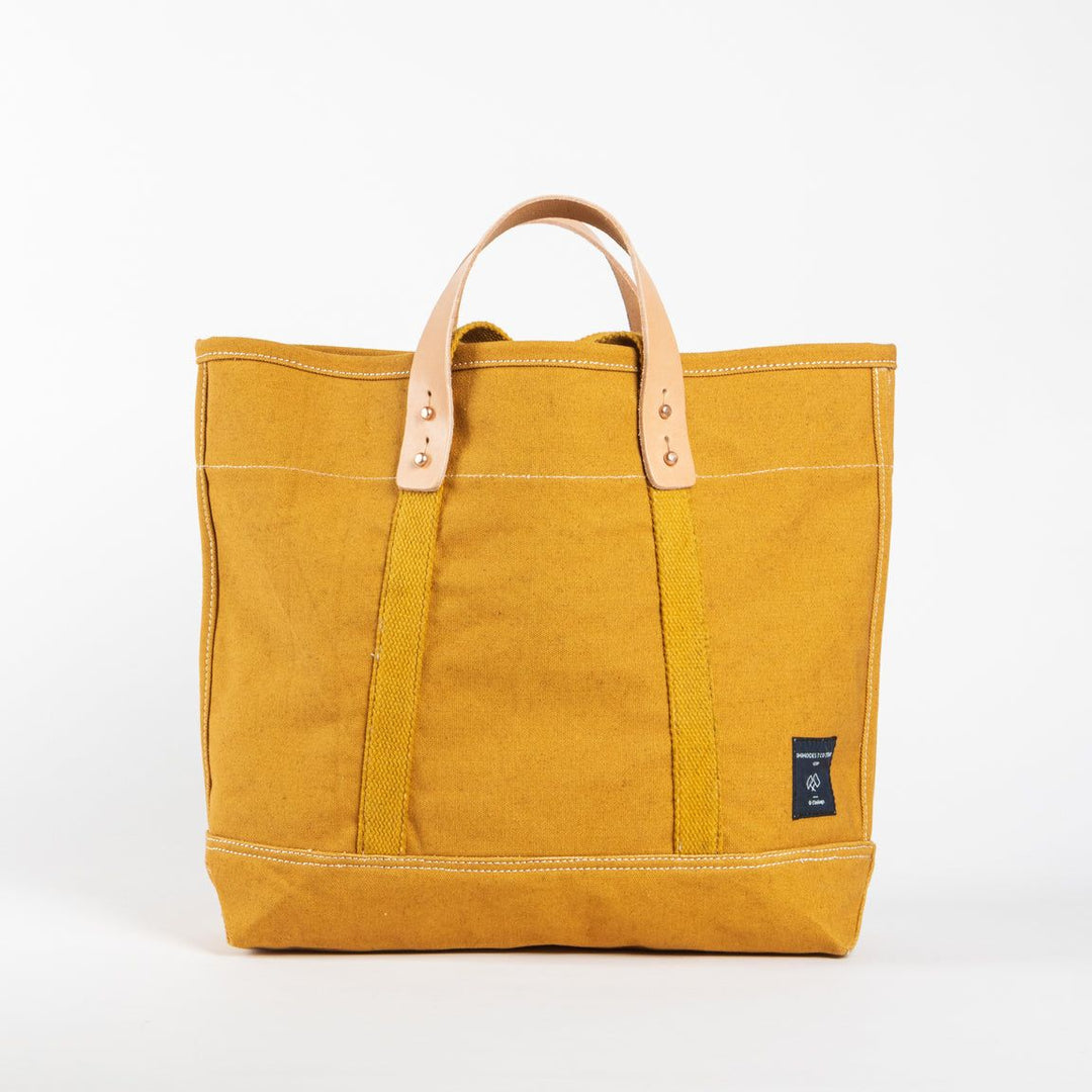 Yellow tote bag with leather handles on a white background