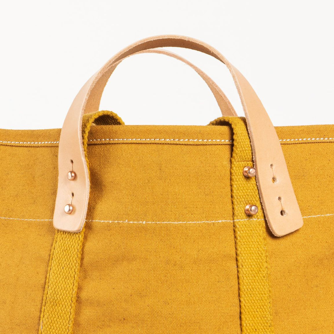 Yellow tote bag with leather handles on a white background