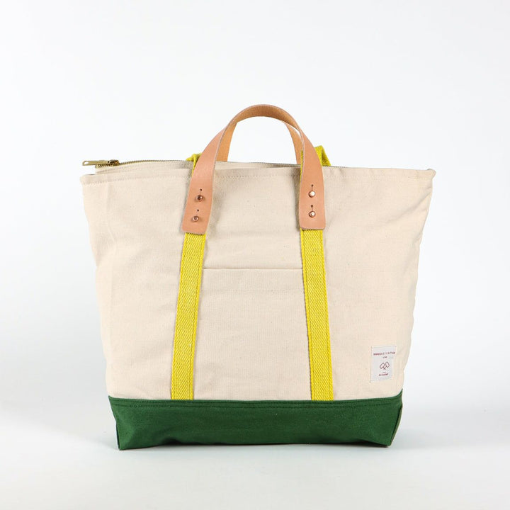 Tote bag with beige top half, yellow side panels, and green bottom half on a white background