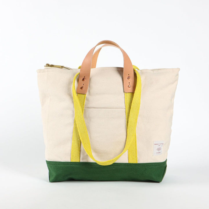 Beige tote bag with yellow strap and green bottom section on a white background