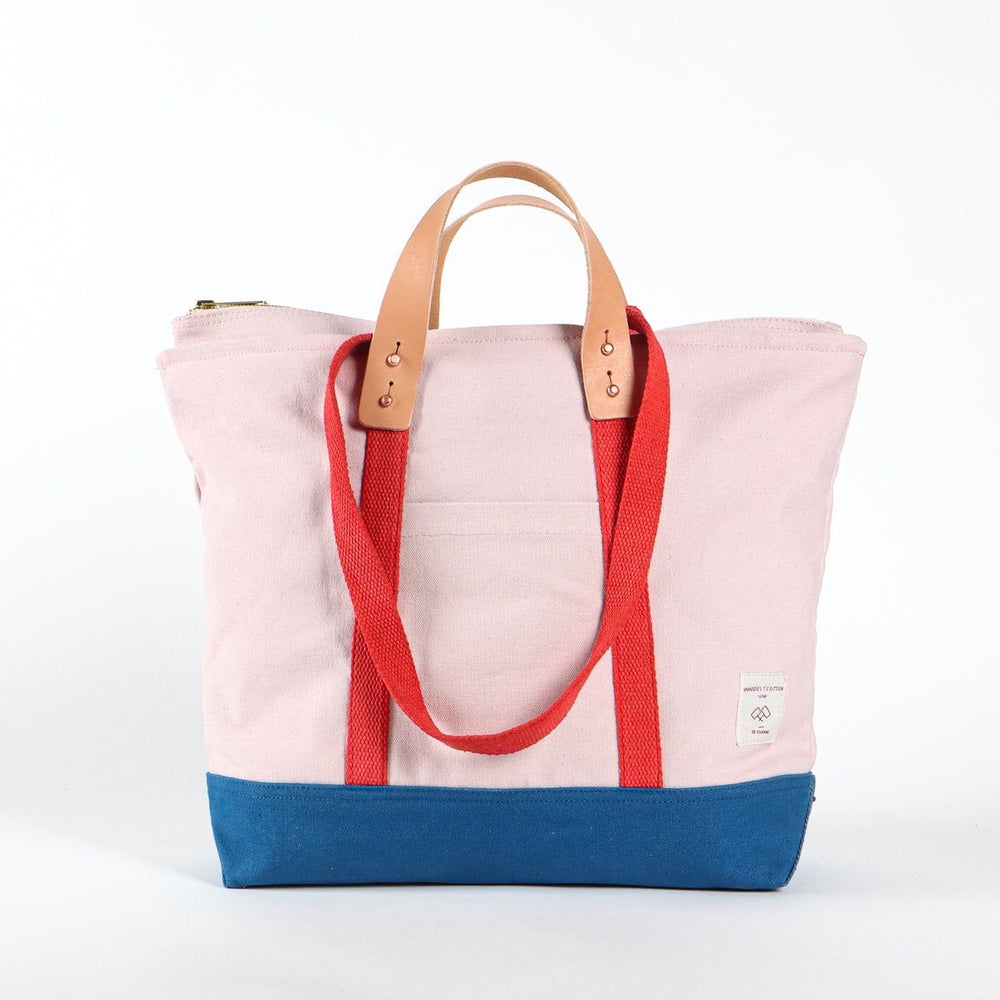 Tote bag with pink top half, red straps, and blue bottom half on a white background