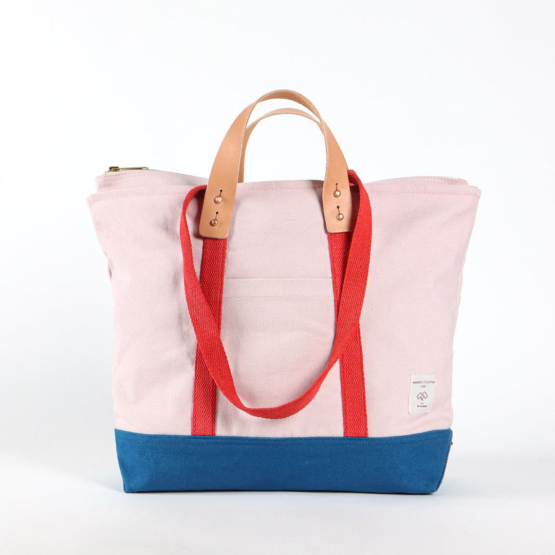 Tote bag with pink top half, red straps, and blue bottom half on a white background