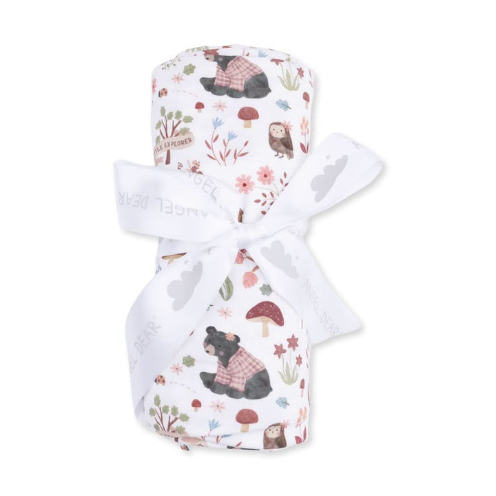 A rolled baby blanket or swaddle with a woodland bear print, tied with a white ribbon, on a plain white background.