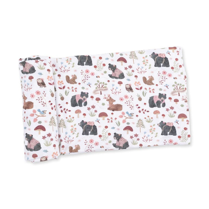 A folded fabric item, likely a blanket or swaddle, featuring a woodland animal print with bears, squirrels, rabbits, mushrooms, and wildflowers on a white background.