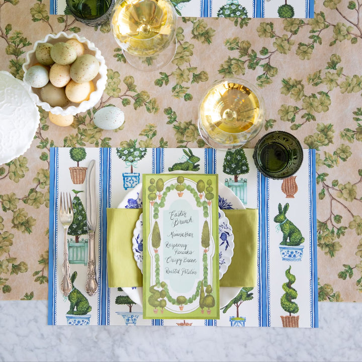 Easter-themed table setting with floral tablecloth, decorative napkins, and place cards.