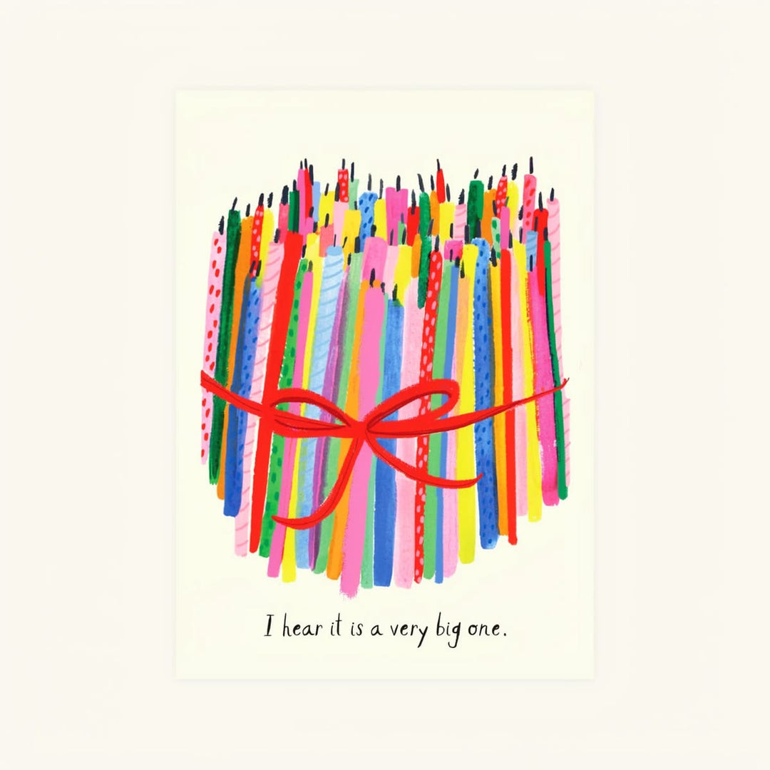 A square greeting card featuring a colorful illustration of stacked birthday candles tied with a red ribbon, with the handwritten text 'I hear it is a very big one.' at the bottom, shown against a light cream background.