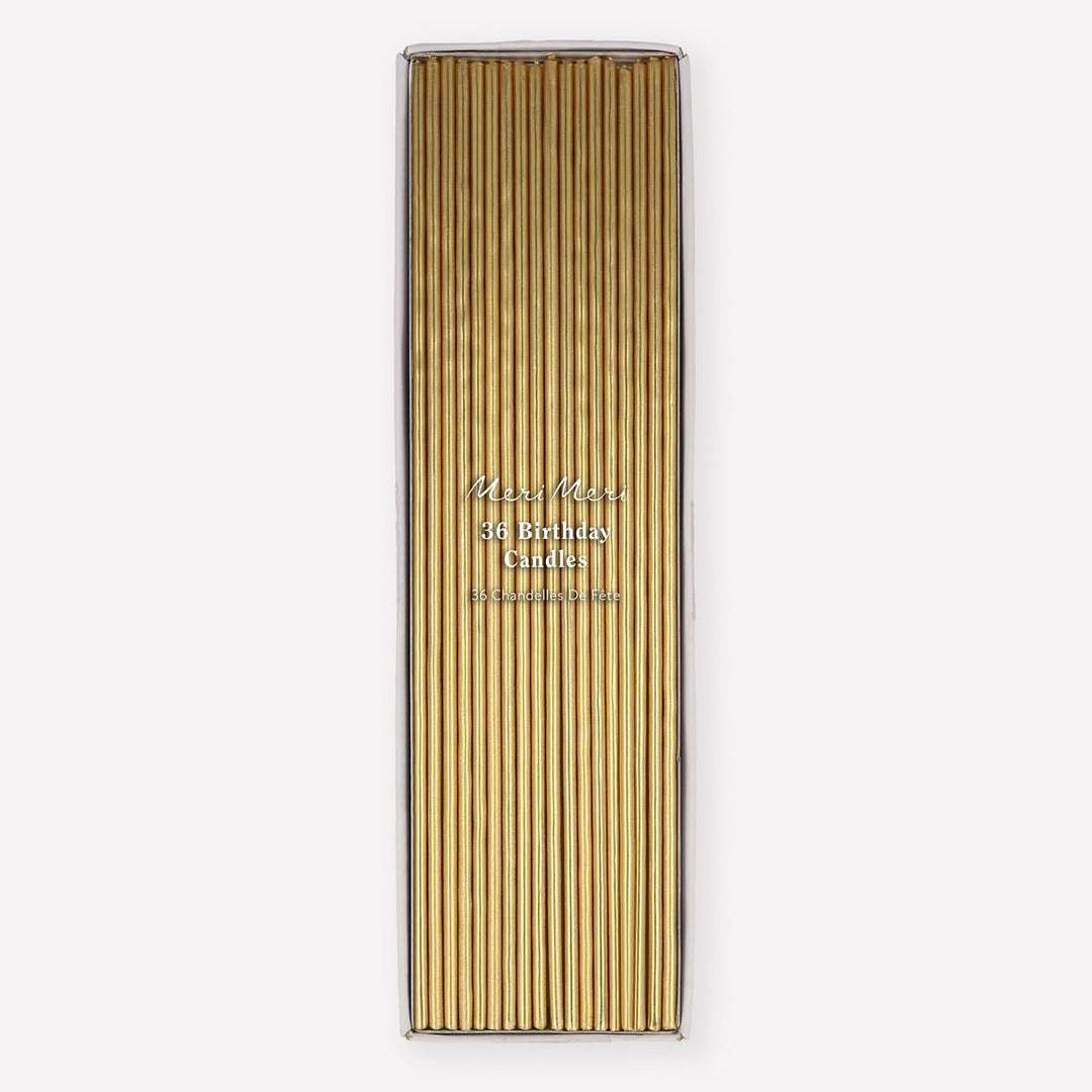 A tall rectangular box of gold birthday candles with a clear top, shown on a plain light gray background. The front has vertical gold candle sleeves and small printed text reading 'Miss Meiss 36 Birthday Candles' and 'Handmade in Germany.