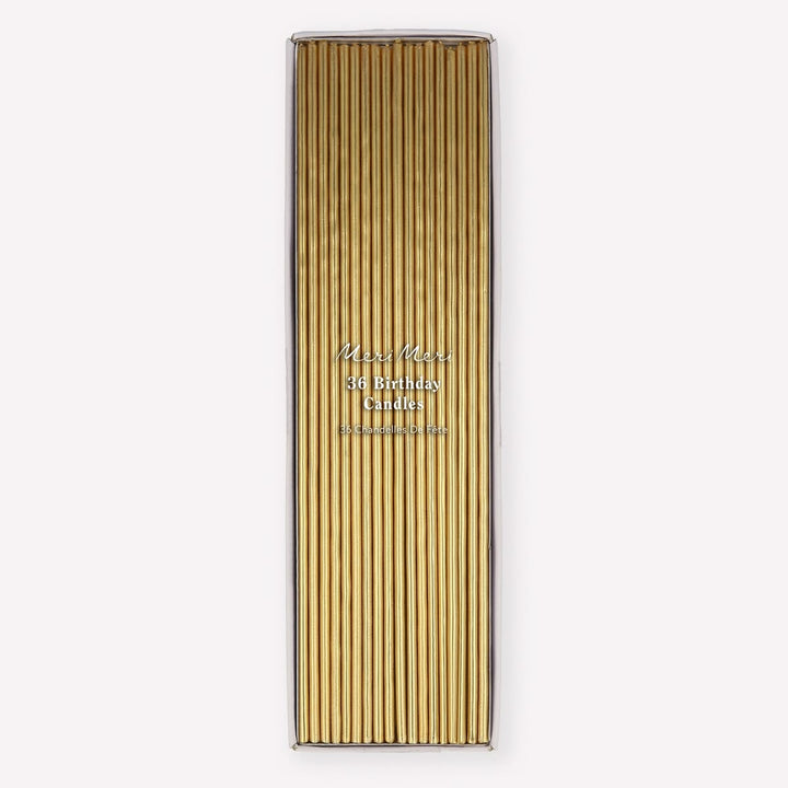 A tall rectangular box of gold birthday candles with a clear top, shown on a plain light gray background. The front has vertical gold candle sleeves and small printed text reading 'Miss Meiss 36 Birthday Candles' and 'Handmade in Germany.