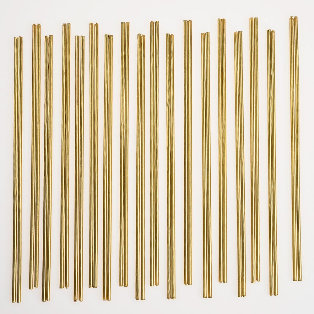 Thirty thin metallic gold rods arranged in vertical rows on a plain white background.