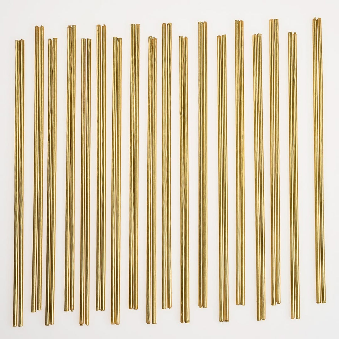 Thirty thin metallic gold rods arranged in vertical rows on a plain white background.