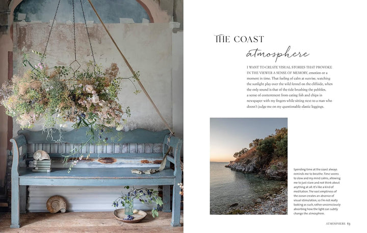 Decorative interior scene with a hanging floral arrangement and bench, alongside a coastal landscape.
