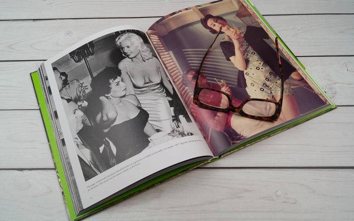 Open book showing black and white and color photographs of a woman on a wooden surface.