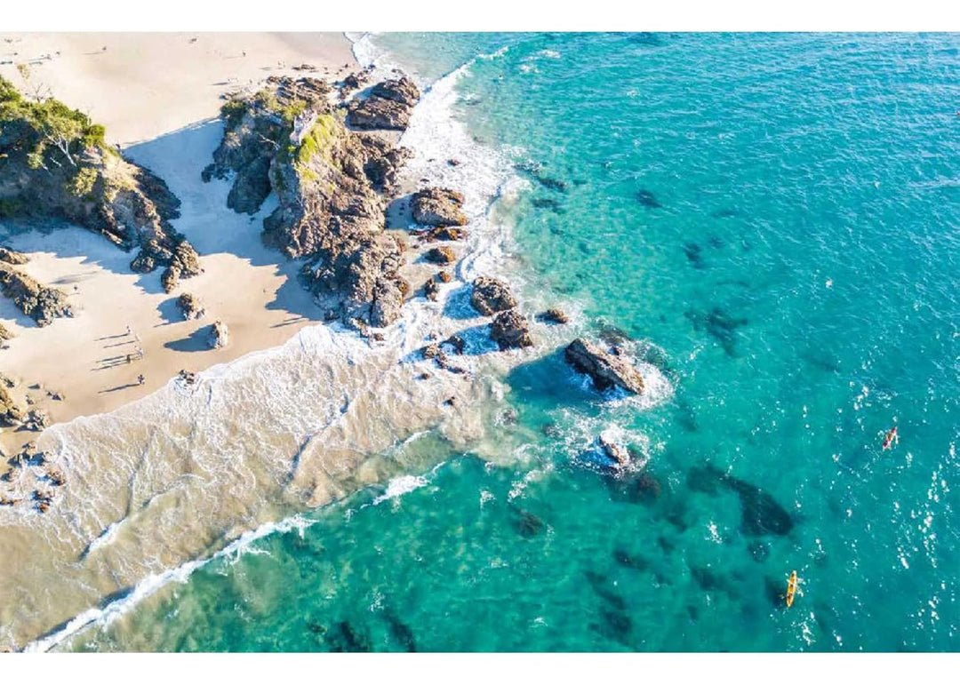 Aerial view of a beach with rocky outcrops and clear blue water.