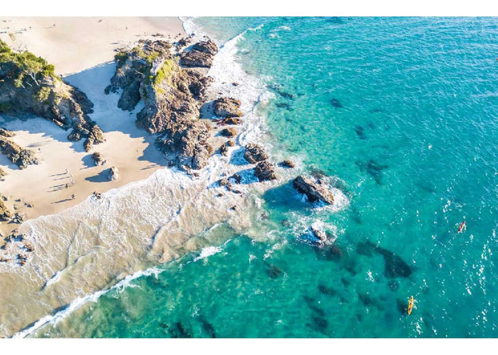 Aerial view of a beach with rocky outcrops and clear blue water.