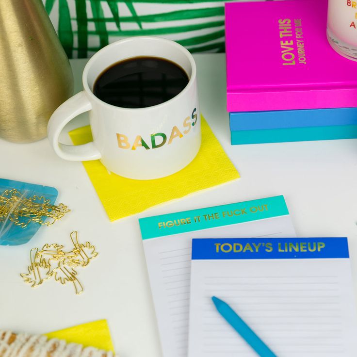 Mug with 'BADASS' text on a desk with office supplies