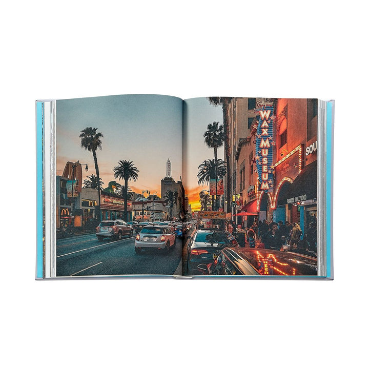 Open book showing a city street scene with palm trees and neon signs.