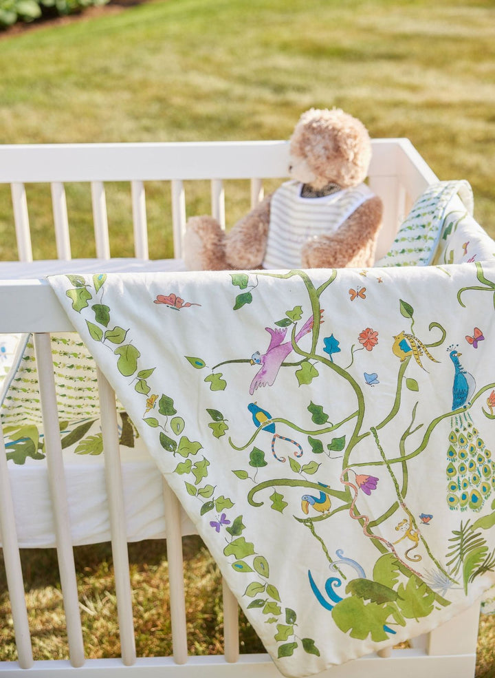Crib with a colorful blanket and teddy bear on a grassy background