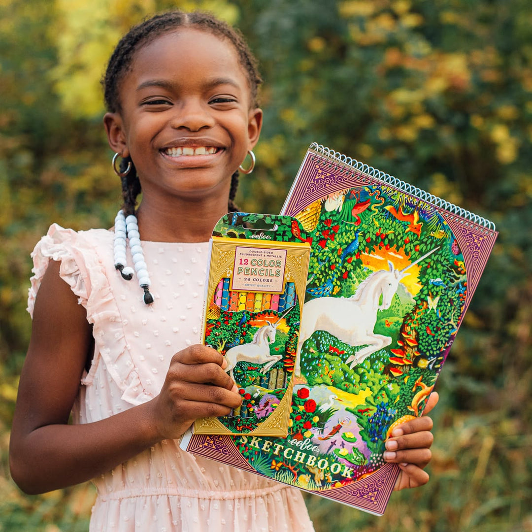 Young girl holding a colorful notebook with unicorn design and a pencil case.