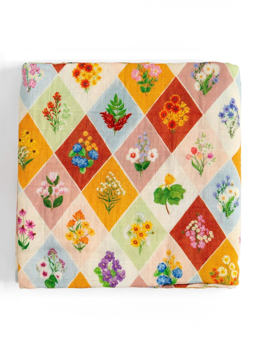 A folded fabric item, likely a blanket or throw, featuring a colorful diamond-patterned print with embroidered floral motifs on a light beige background.