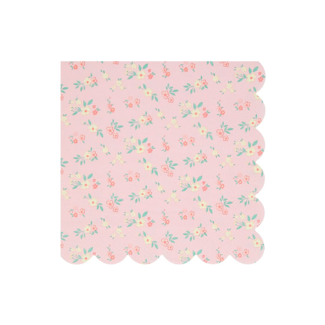 A square pink paper napkin with a scalloped edge, featuring a delicate all-over floral print in soft coral, yellow, and mint green on a light pink background.