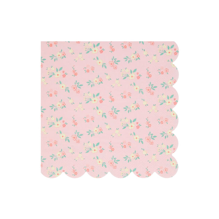 A square pink paper napkin with a scalloped edge, featuring a delicate all-over floral print in soft coral, yellow, and mint green on a light pink background.