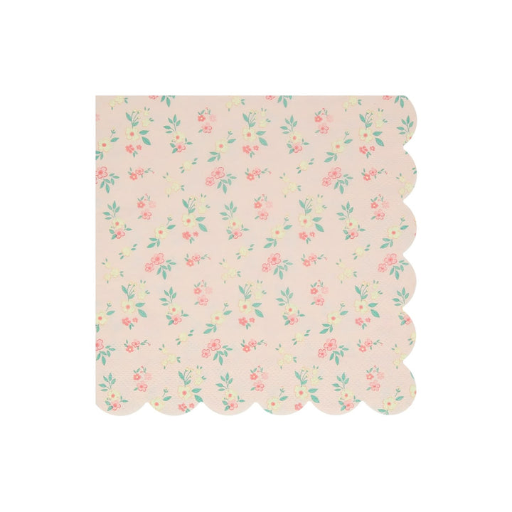 A square paper napkin with a scalloped edge, featuring a delicate pastel floral pattern on a light pink background.
