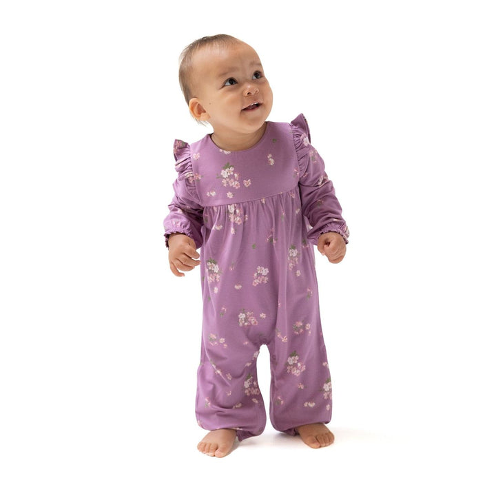 Baby wearing a purple floral onesie on a white background